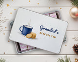Personalised biscuit tin with "Grandad's Biscuit Tin" lid, front view on a festive white wood table
