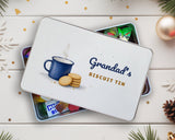 Biscuit tin personalised with a name, lid resting on a tin of wrapped sweets on a festive table