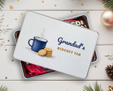 Personalised biscuit tin with "Grandad's Biscuit Tin" lid on a tin filled with chocolates and sweets, Christmas decorations around