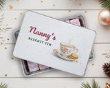 Personalised biscuit tin with "Nanny's Biscuit Tin" lid, front view on a festive white wood table