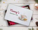 Personalised biscuit tin with "Nanny's Biscuit Tin" lid on a tin filled with chocolates and sweets, Christmas decorations around